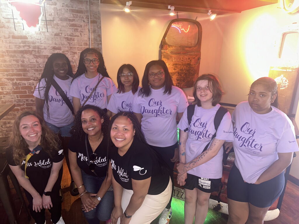 girls and young women wearing purple shirts that say 'our daughter'