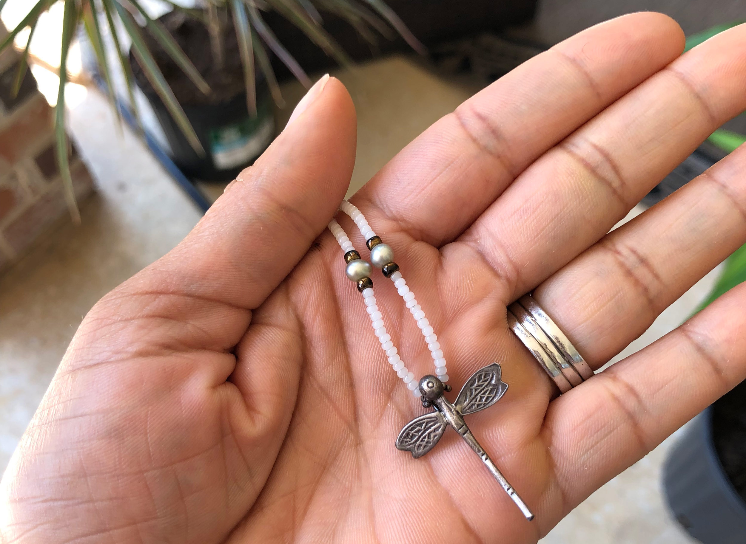 hand holding a dragonfly necklace