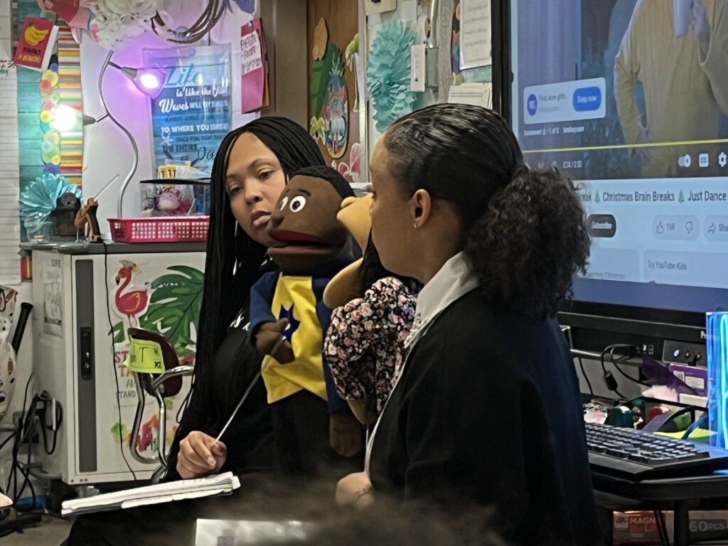 amber and a teacher demonstrating with a puppet