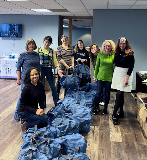 Volunteers from Spirit of St. Louis Women’s Fund assembling SOS kits. There is a pile of blue duffel bags.